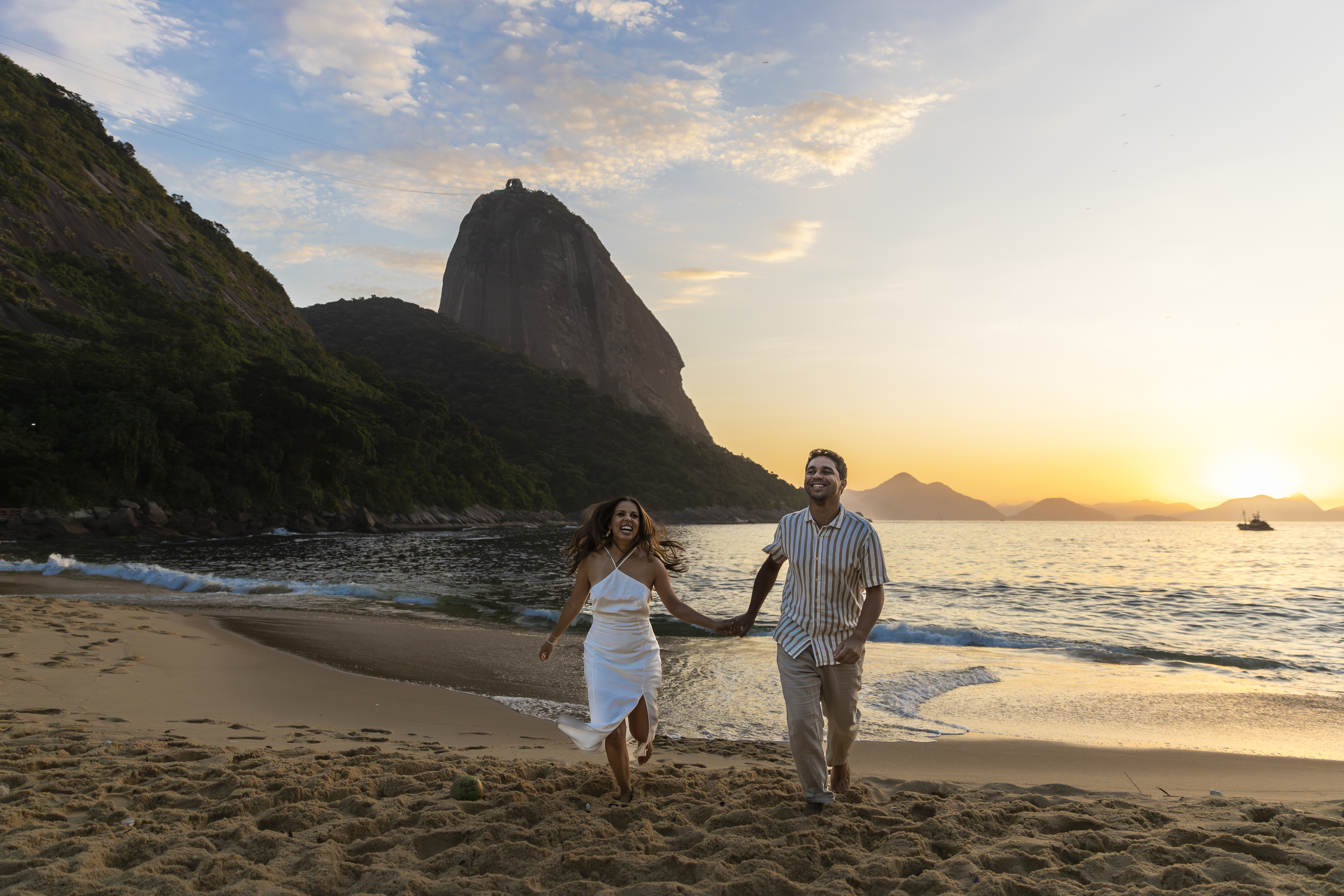 Couple running on the beach at sunrise with Sugarloaf Mountain